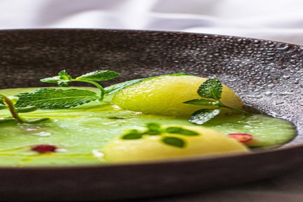 A bowl of vibrant green Spring Pea and Mint Soup garnished with mint.