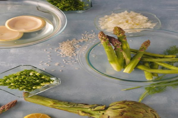 Ingredients for artichoke risotto, including artichokes, Arborio rice, and broth.